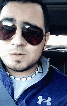 a man wearing sunglasses and a under armour jacket
