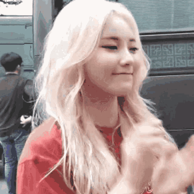 a woman with blonde hair is wearing a red shirt and making a face .