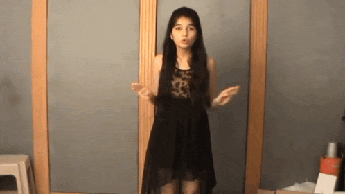 a girl in a black dress is standing in front of a mirror