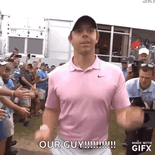 a man in a pink shirt is standing in front of a crowd and saying our guy .