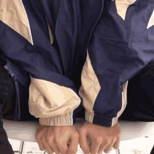 a person sitting on a chair with their hands folded in front of them