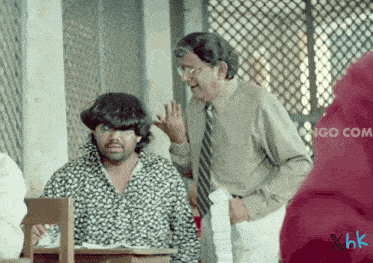 a man in a suit and tie is talking to another man in a classroom with xhk written in the corner