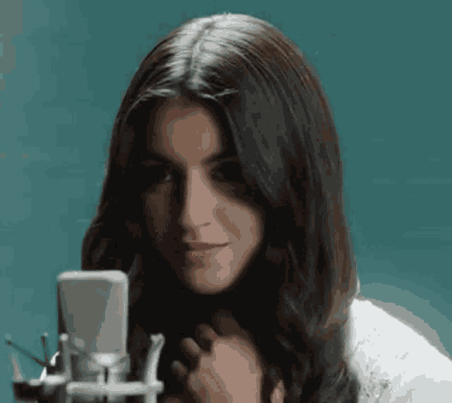 a woman is singing into a microphone and smiling .