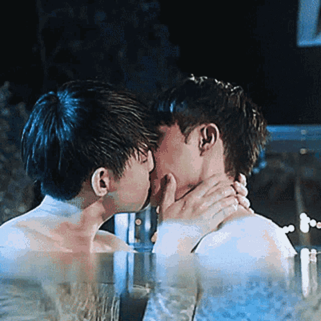 a couple of men kissing in a pool at night