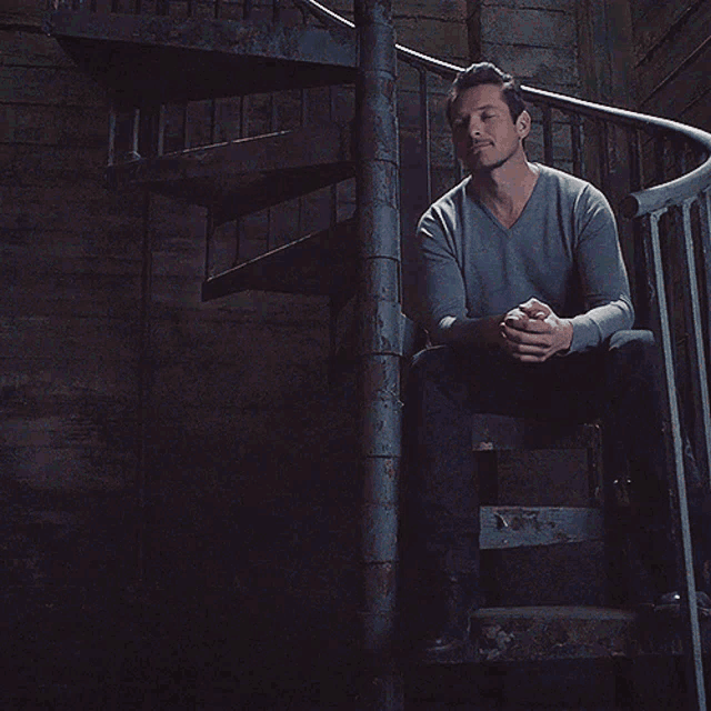 a man sits on a set of spiral stairs