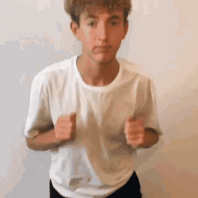 a young man in a white t-shirt is making a funny face .