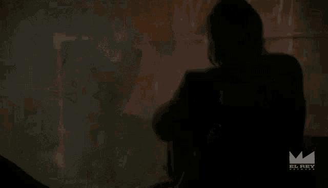 a man in a suit is standing in a dark room holding a knife .