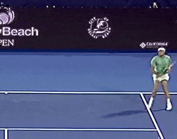 a man is playing tennis on a court with a city of sunny beach open banner behind him