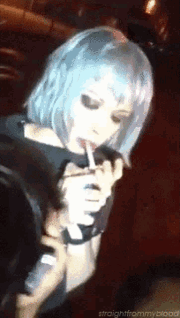 a woman with blue hair is applying lipstick in front of a microphone with the words straightfrommyblood below her