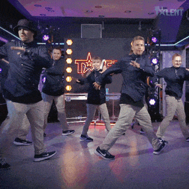 a group of people are dancing in front of a neon star that says talent