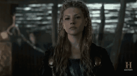 a woman with braids in her hair is standing in front of a window in a dark room .
