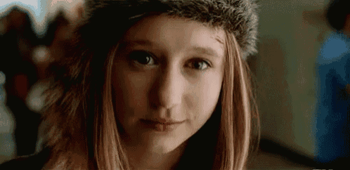 a young girl wearing a fur hat is looking at the camera .
