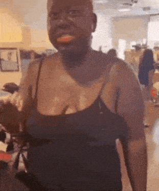 a woman is standing in a room wearing a black tank top and smiling .