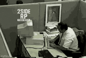 a man is sitting at a desk in front of a computer in a cubicle .