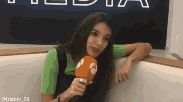 a woman in a green shirt is holding a microphone in her hand .