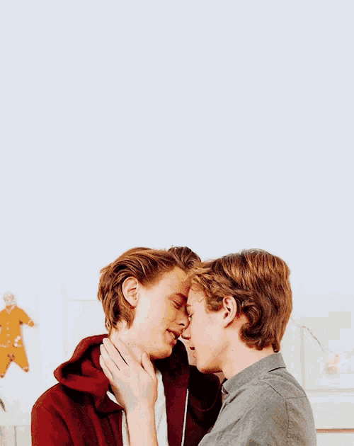 two young men are touching their noses against a white wall