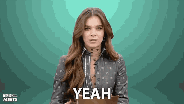 a woman in a denim shirt says yeah in front of a green background