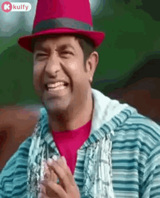 a man wearing a red hat and a striped jacket is laughing .