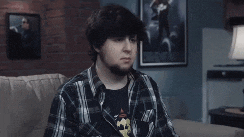 a man in a plaid shirt is sitting on a couch in front of a picture of a man on a motorcycle