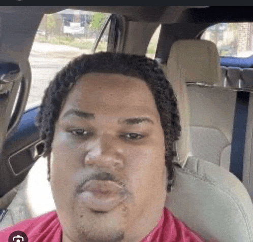 a man is sitting in the back seat of a car and looking at the camera .