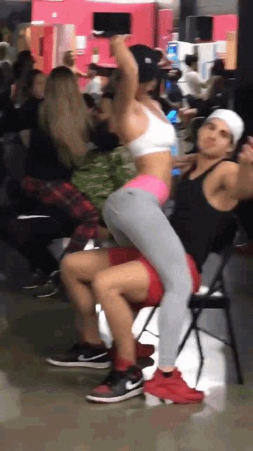 a man is carrying a woman on his back in a crowded gym