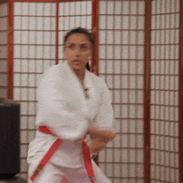 a woman in a white karate uniform has a red belt around her waist