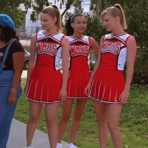 three wmhs cheerleaders are standing next to each other on a sidewalk