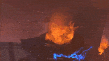 a fire is coming out of a building and a person is standing in front of it .