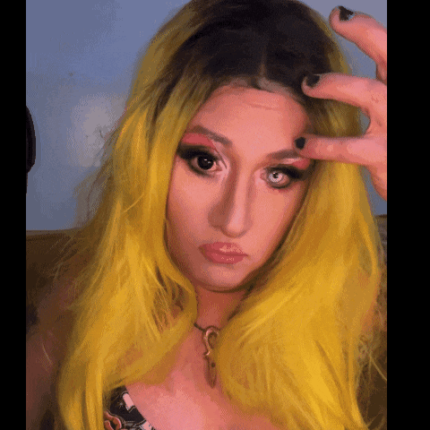 a woman with yellow hair is taking a picture with her hand