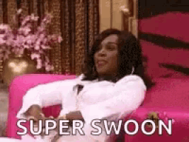 a woman is sitting on a pink couch with the words `` super swoon '' .
