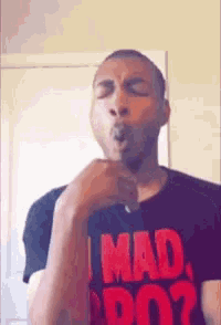 a man wearing a t-shirt that says i mad do ? is smoking a cigarette