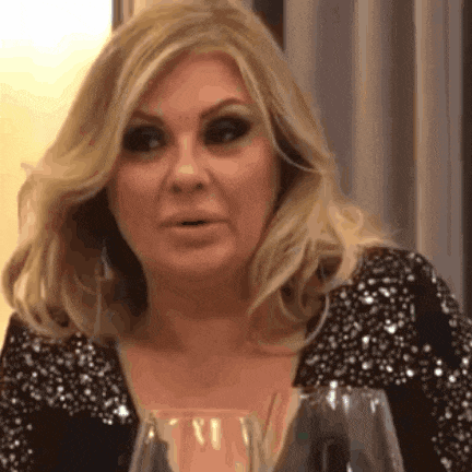 a woman in a black dress is sitting at a table with a glass of wine .