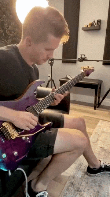 a man is playing a purple electric guitar in a room