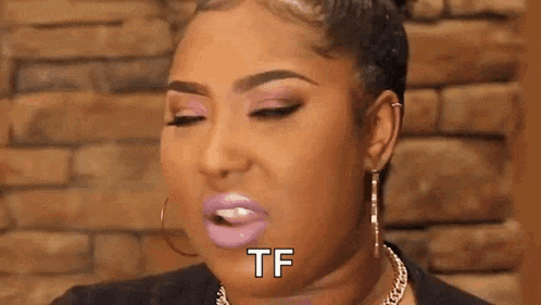 a woman with pink lipstick and earrings is making a funny face and saying `` tf '' .