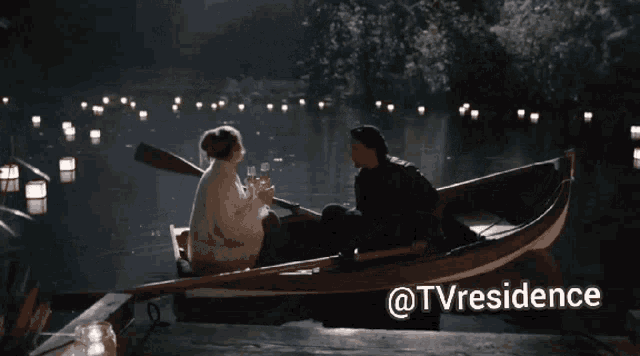 a man and a woman in a boat on a lake with candles in the background