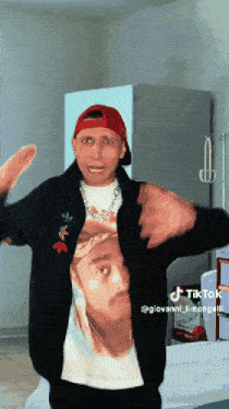 a man wearing a black jacket and a red hat has a picture of a man on his shirt