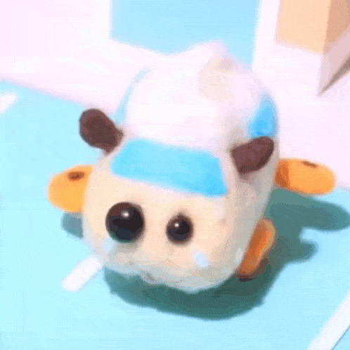a stuffed animal is sitting on a blue surface and looking at the camera .