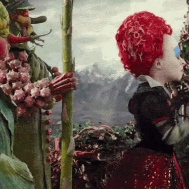 a little girl with red hair is standing next to a giant plant