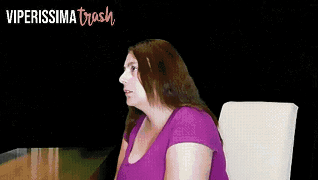 a woman in a purple shirt sits in front of a blackboard with viperissima trash written in pink