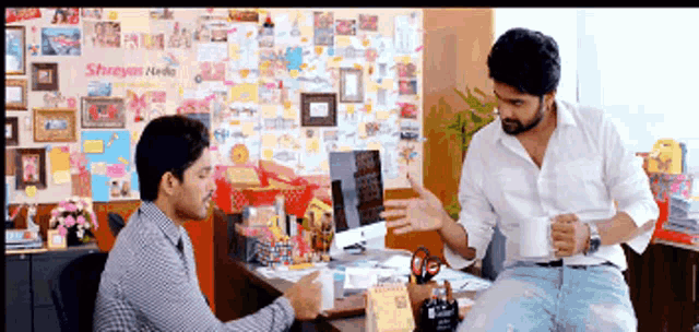 two men are having a conversation in front of a wall that says ' shreeyan media '