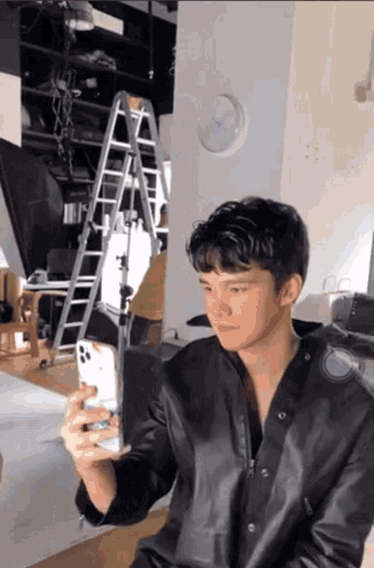 a man in a black leather jacket is taking a picture of himself with his phone