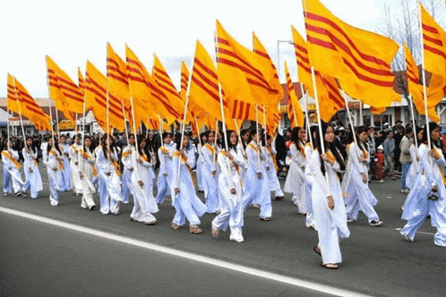 a large group of people marching down a street holding yellow flags