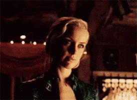 a woman in a green leather jacket is looking at the camera in a dark room .