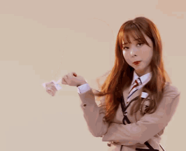 a young girl in a school uniform and tie is holding a piece of paper in her hand .