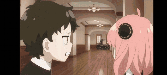 a boy and a girl are standing in a hallway and looking at each other