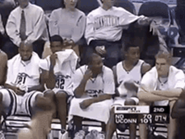 a group of uconn basketball players sit on the bench