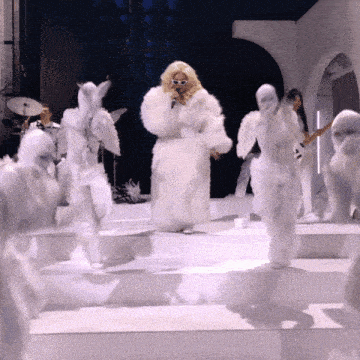 a woman in a white fur coat is singing on stage