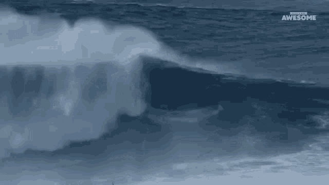 a large wave is breaking in the ocean with the words awesome on the bottom right