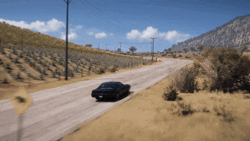 a car is driving down a dirt road with a mountain in the background