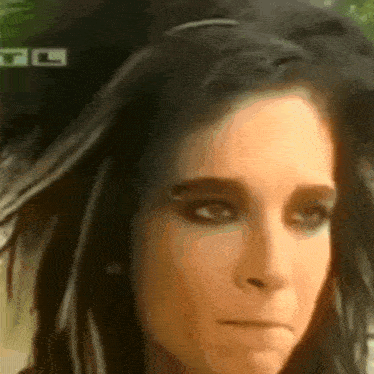 a close up of a woman 's face with a tl sign in the background